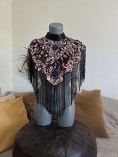 a mannequin is adorned with fringes and beads on top of a leather ottoman