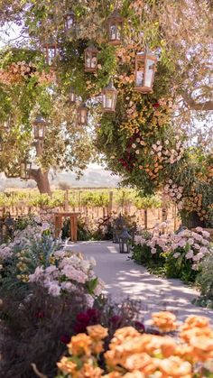 an outdoor ceremony area with flowers and lanterns hanging from the trees overhanging it