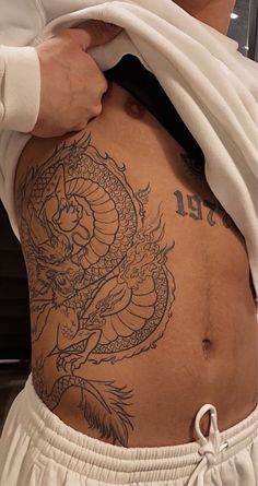 a man with a dragon tattoo on his stomach and back is shown from the waist up