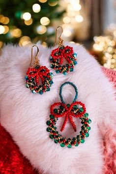 a pair of red, green and blue beaded christmas wreath earrings on a white furnishing