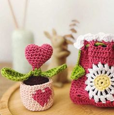 two crocheted boots sitting on top of a wooden table next to a potted plant