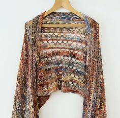 a multicolored crocheted shawl hanging on a wooden hanger