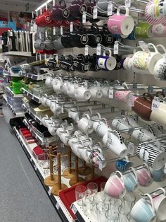 there are many cups and mugs on the shelves in this store, all lined up