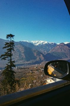 a car mirror with mountains in the background