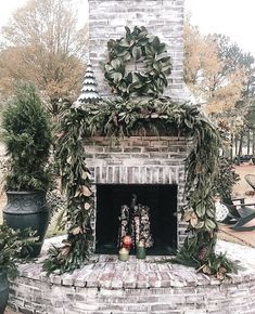 a brick fireplace is decorated with greenery and potted plants in front of it