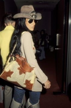 a woman with a cowboy hat and boots carrying a purse