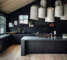 an image of a kitchen setting with black and white decor on the walls, wood flooring and hanging lights