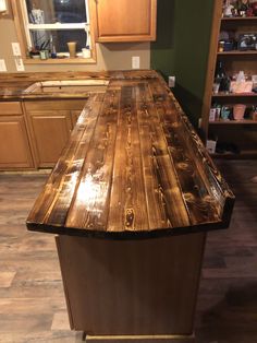 a kitchen island made out of wood in the middle of a floored room with cabinets