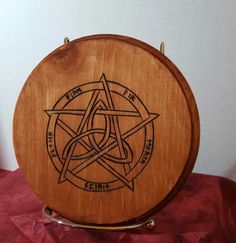 a wooden plaque with an inverted pentagram design on the front and sides, sitting on a red velvet surface