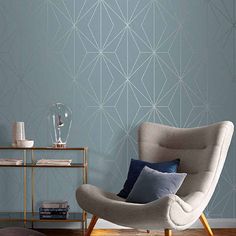 a living room with a chair, table and wallpaper on the walls in shades of blue