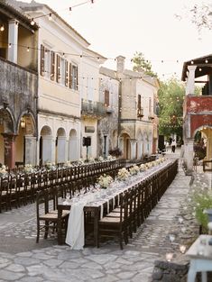 an outdoor dining area with tables and chairs set up in front of the building for a formal function