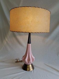 a pink lamp sitting on top of a table next to a white cloth covered wall