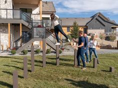 three people are playing in the yard with their dog and another person is standing on top of them