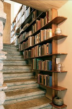 there are many books on the shelves next to the stairs