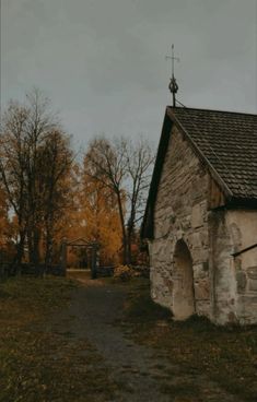 an old stone building with a weather vane on top and trees in the back ground