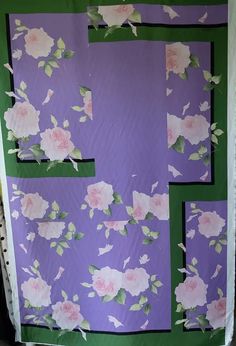 a quilt made to look like flowers on a purple and green background with black border