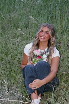 a beautiful young woman sitting in the grass