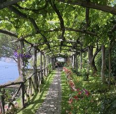 a pathway lined with trees and flowers next to the water