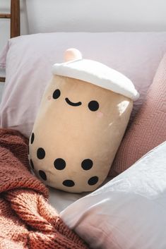 a coffee cup pillow sitting on top of a bed next to a blanket and pillows