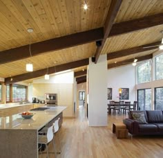 a large open kitchen and living room with wood flooring in the middle of it