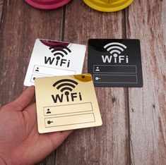 a hand is holding a wifi card next to some other items on a wooden table