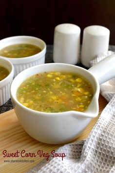 three white bowls filled with soup sitting on top of a wooden cutting board next to salt and pepper shakers