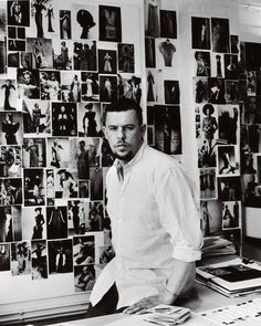 a man standing in front of a wall covered with pictures and photos on the walls