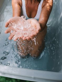 a woman sitting in a bathtub with water splashing on her hands and the tub is full of bubbles