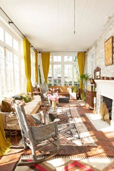 a living room filled with furniture and a fire place next to a window covered in yellow curtains