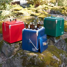 three coolers sitting on top of a moss covered rock