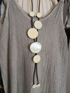 a white and black necklace is hanging on a gray shirt with two discs attached to it