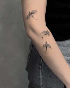 a woman's arm with three bats on it and one is flying in the air