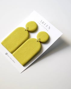 a pair of yellow earrings sitting on top of a card