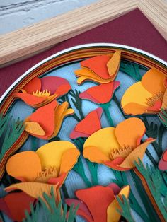 paper cut flowers are arranged in a circle on a plate with red and yellow trim