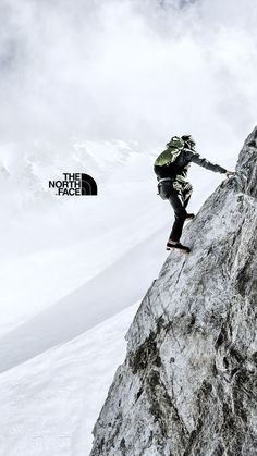 a man climbing up the side of a snow covered mountain