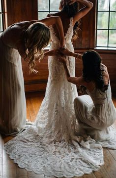 three bridesmaids helping each other get ready for their wedding at the same time