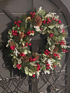 a wreath with pine cones, holly and red berries