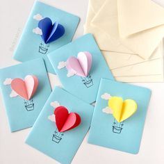 four different colored paper hearts on blue envelopes