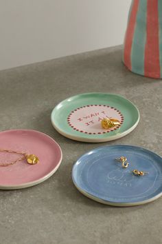 three plates with designs on them sitting on a table next to a vase and other items