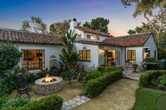 a house with a fire pit in the front yard and landscaping around it at sunset