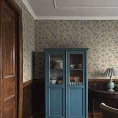 a blue cabinet sitting in the corner of a room next to a table and chair