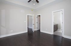 an empty living room with hard wood flooring and white paint on the walls, along with a ceiling fan