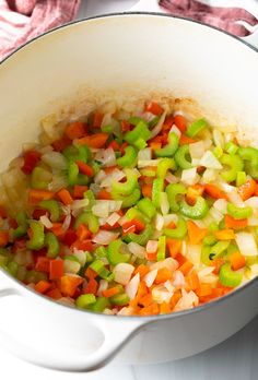 a pot filled with vegetables sitting on top of a stove next to a red and white towel