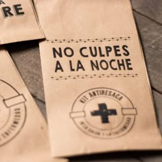 three brown paper bags with black and white logos on them sitting on a wooden table