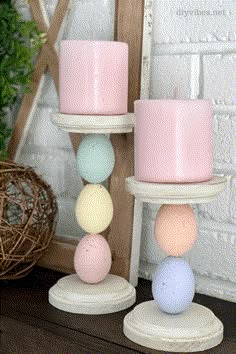 two candles sitting next to each other on top of a wooden stand with eggs in them