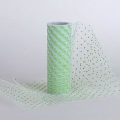 a roll of green and white polka dot tape on a white background with one roll in the foreground