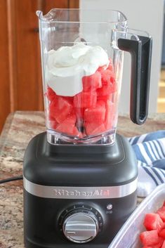 a blender filled with watermelon cubes on top of a kitchen counter