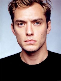 a close up of a person wearing a black shirt and looking at the camera with a serious look on his face