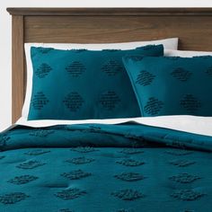 a bed with teal colored comforters and pillows