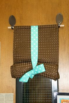 a kitchen window curtain with polka dots and blue ribbon tied to the side, hanging on a metal rod